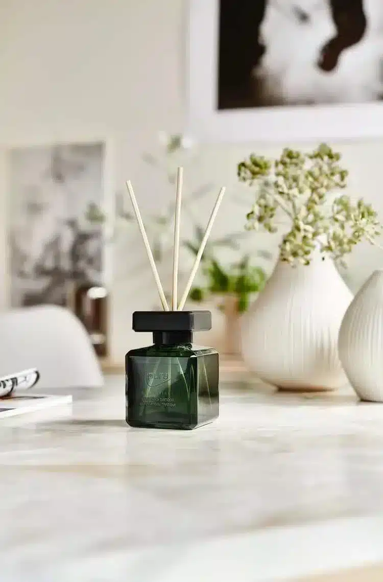 Ipuro Essentials Black Bamboo geurstokjes in donkergroen flesje op tafel met vaas en groen