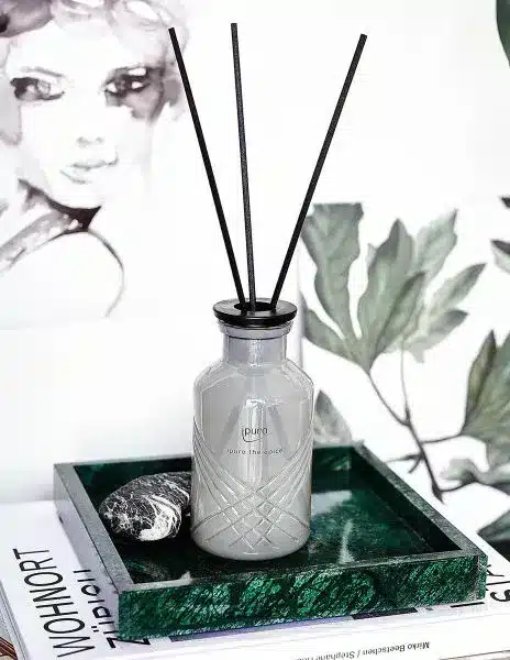 Bâtonnets parfumés ipuro Exclusive thé épicé 240ml en flacon gris sur un plateau avec branches vertes